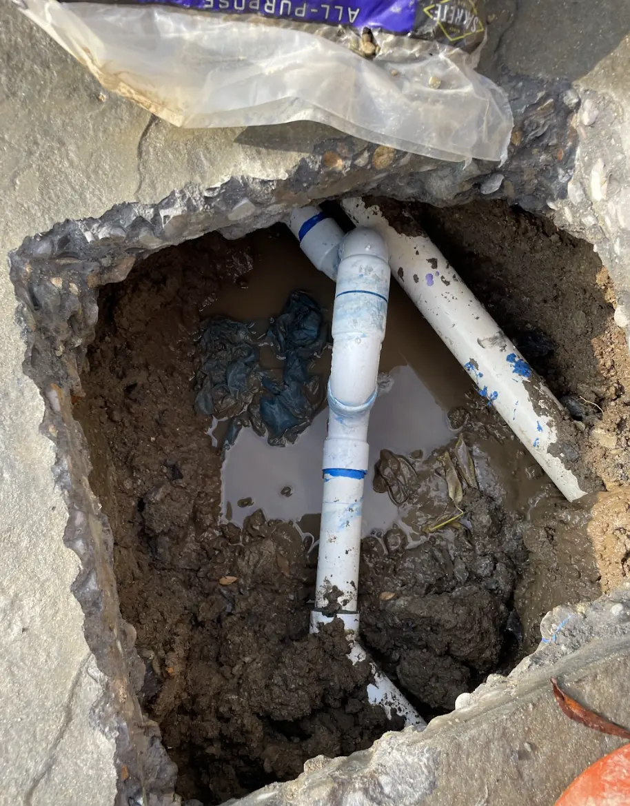 New PVC water line section in an excavated hole cut through concrete